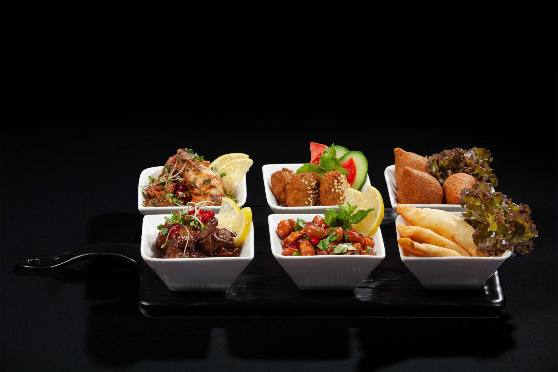 A tantalizing array of Middle Eastern appetizers beautifully plated in square bowls, perfect for a gourmet feast.