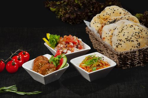 Free A delicious spread of Middle Eastern dishes featuring sesame bread, fresh dips, and cherry tomatoes. Stock Photo