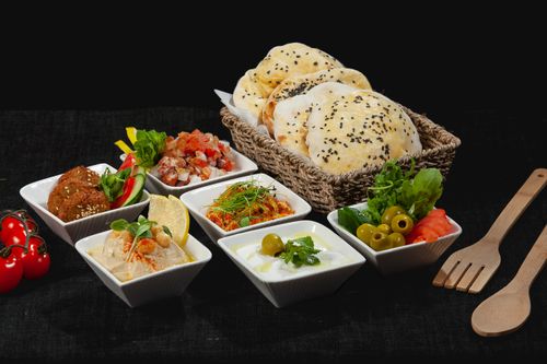 Free A variety of Middle Eastern dishes with fresh pita bread in a woven basket, perfect for sharing. Stock Photo