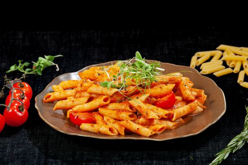 Free Close-up of penne pasta with tomato sauce and fresh garnish on a plate. Stock Photo