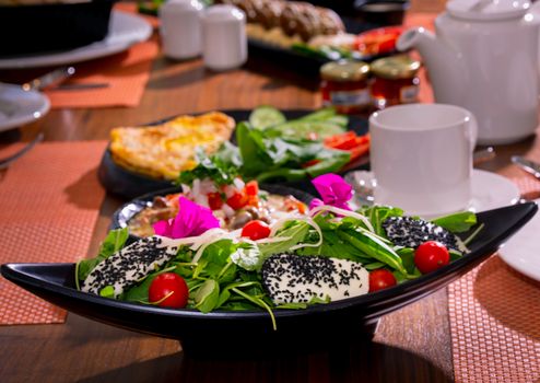 A vibrant salad with fresh greens, sesame cheese, and edible flowers.