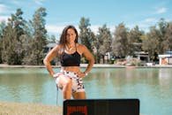 Woman in Black Brassiere and White and Black Floral Shorts Standing on Brown Sand Near Body