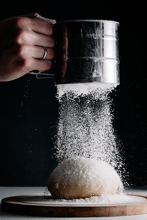 Free Hand Pouring Flour on Dough Bun Stock Photo