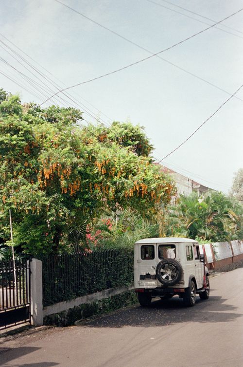 Free A vintage jeep parked on a quiet residential street in Bandung, surrounded by lush greenery. Stock Photo
