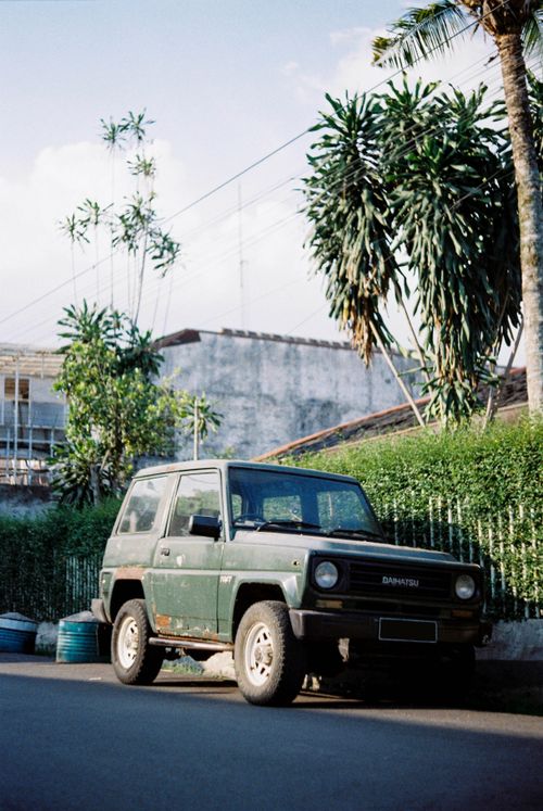 Free A vintage car parked outdoors in Bandung, Indonesia, surrounded by lush greenery. Stock Photo