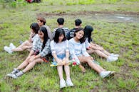 Men and Women Sitting on Grass Forming Circle of Friends
