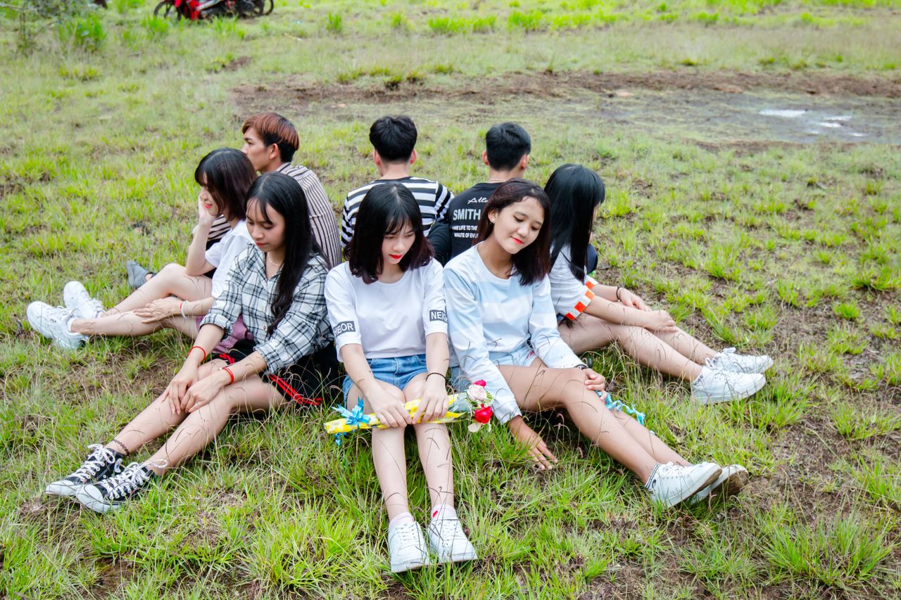 a group of teenagers relaxing on grass enjoying a sunny day together