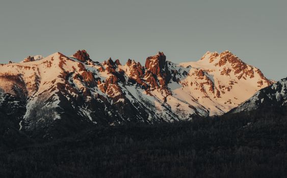 Dramatic snowy mountain peaks illuminated by the warm light of sunrise.