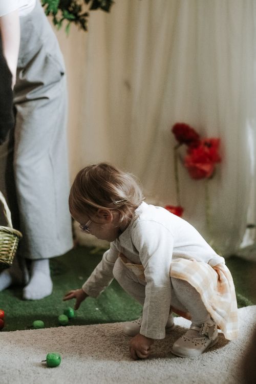 Free Child in cozy indoor setting playing with green toys on a carpeted floor. Stock Photo