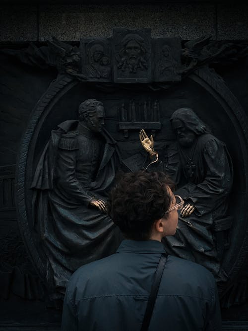 Person Standing in Front of Black Statue with Gold Hands