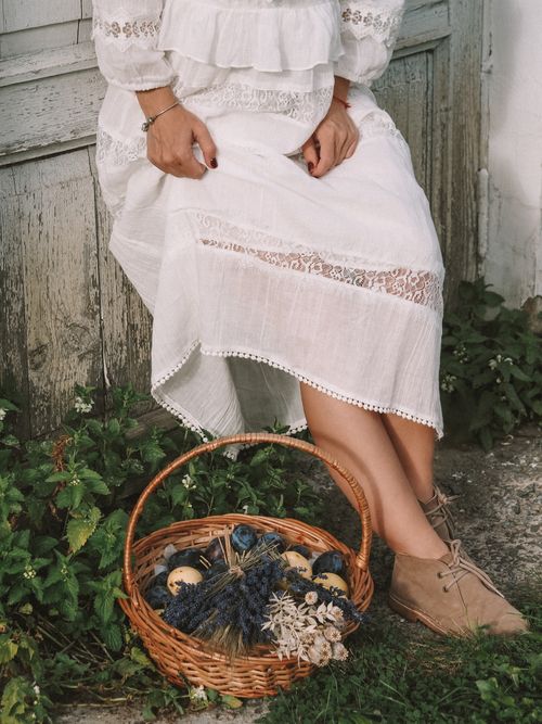 Free Woman in white dress holding a basket with harvested fruits and flowers by an old door. Stock Photo