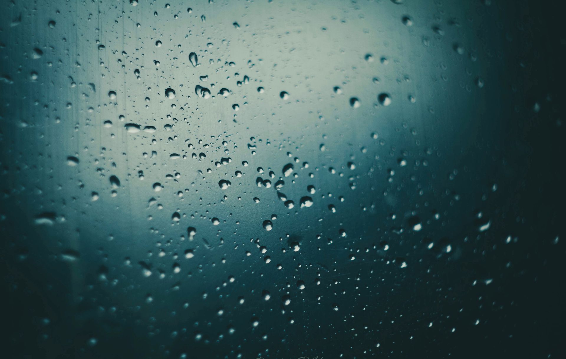 Close-up of rain drops on a glass surface creating a moody and atmospheric scene.