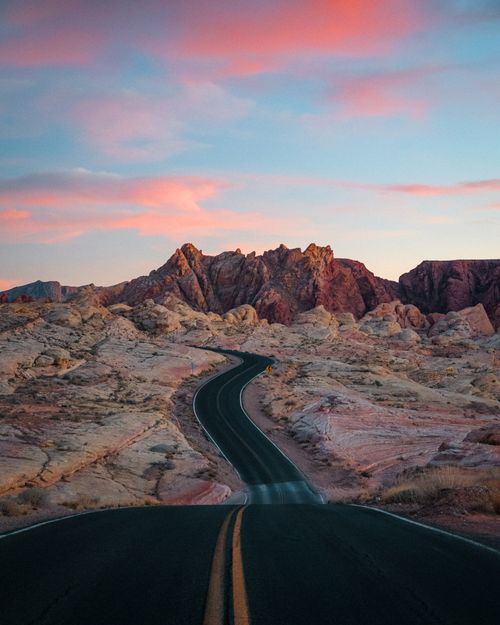 Free A winding road cuts through a rocky desert landscape at sunset in Nevada. Stock Photo