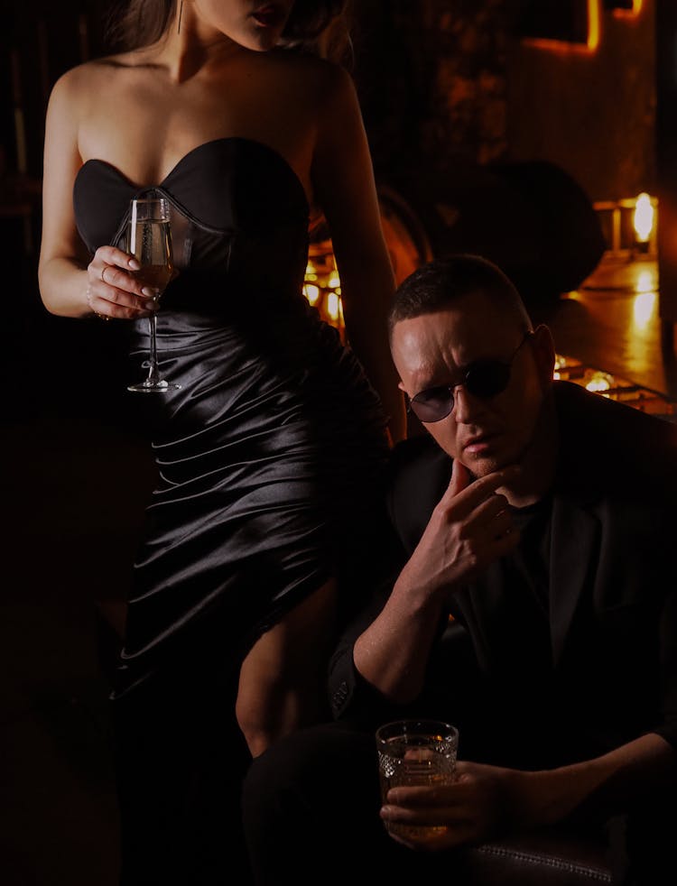 A Couple In Black Attire Holding A  Glass Of Alcoholic Beverages