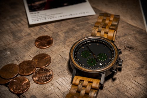 A Wrist Watch with Wooden Bracelet Beside Coins 