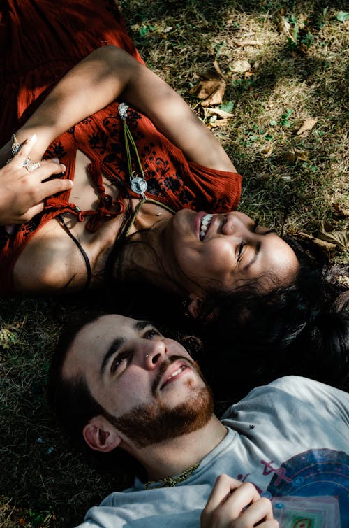 Free A Happy Man and Woman Lying on a Grass Field Stock Photo