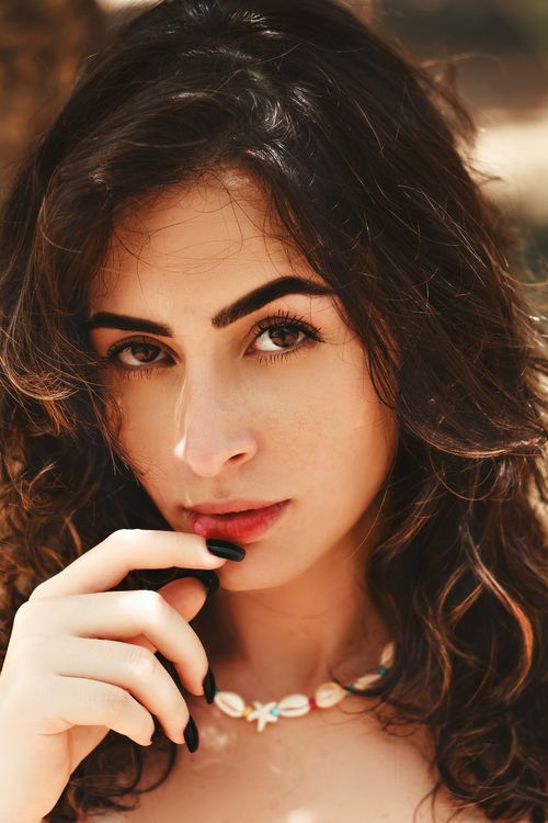 Free Close-up portrait of a woman with wavy hair and natural makeup, exuding elegance and beauty. Stock Photo