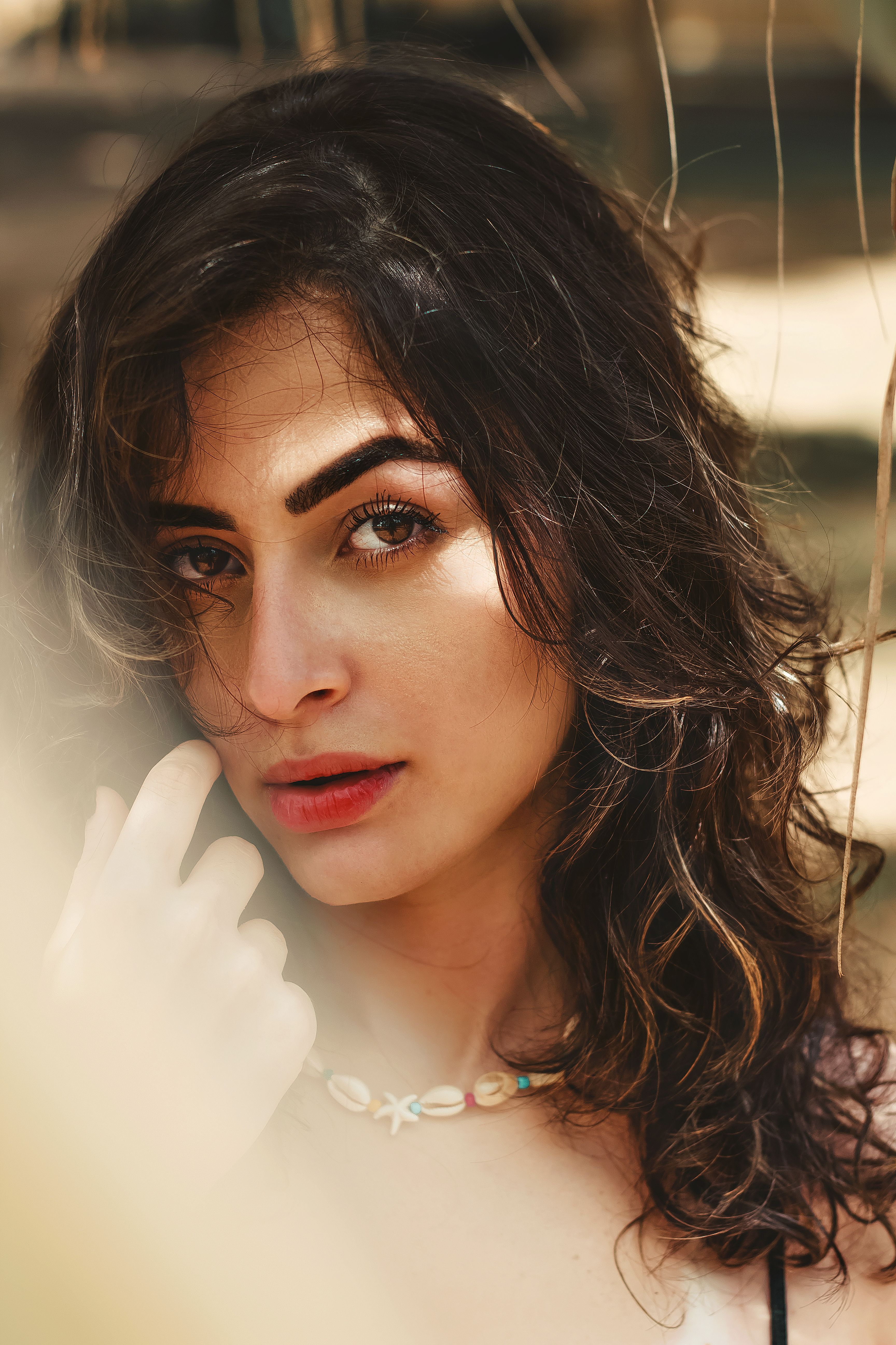 Close-up portrait of a woman with wavy hair outdoors in natural lighting.