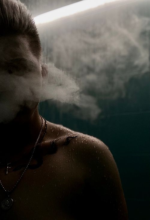 Free A shirtless man enveloped in smoke and steam, creating a mysterious atmosphere. Stock Photo