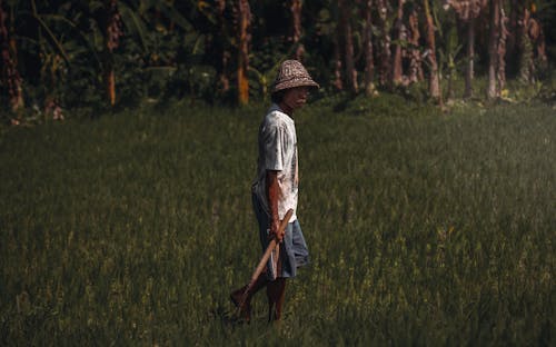 Man in White Shirt Walking on Green Grass Field