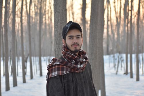 Free Portrait of a young man with a scarf in a serene winter forest. Stock Photo