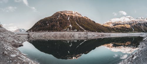 Montagne Couverte Verte Reflétée Sur L'eau Calme Sous Un Ciel Clair Photo De Paysage