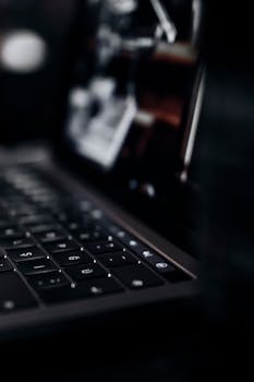 A detailed close-up of a laptop keyboard in a dark setting, showcasing technology.