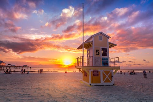 White and Yellow Wooden Lifeguard House on Beach during Sunset