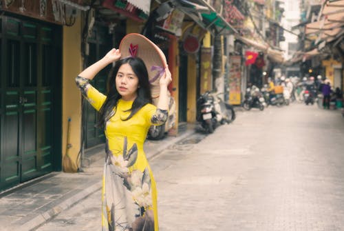 Woman Wearing a Yellow Printed Dress Walking on the Street