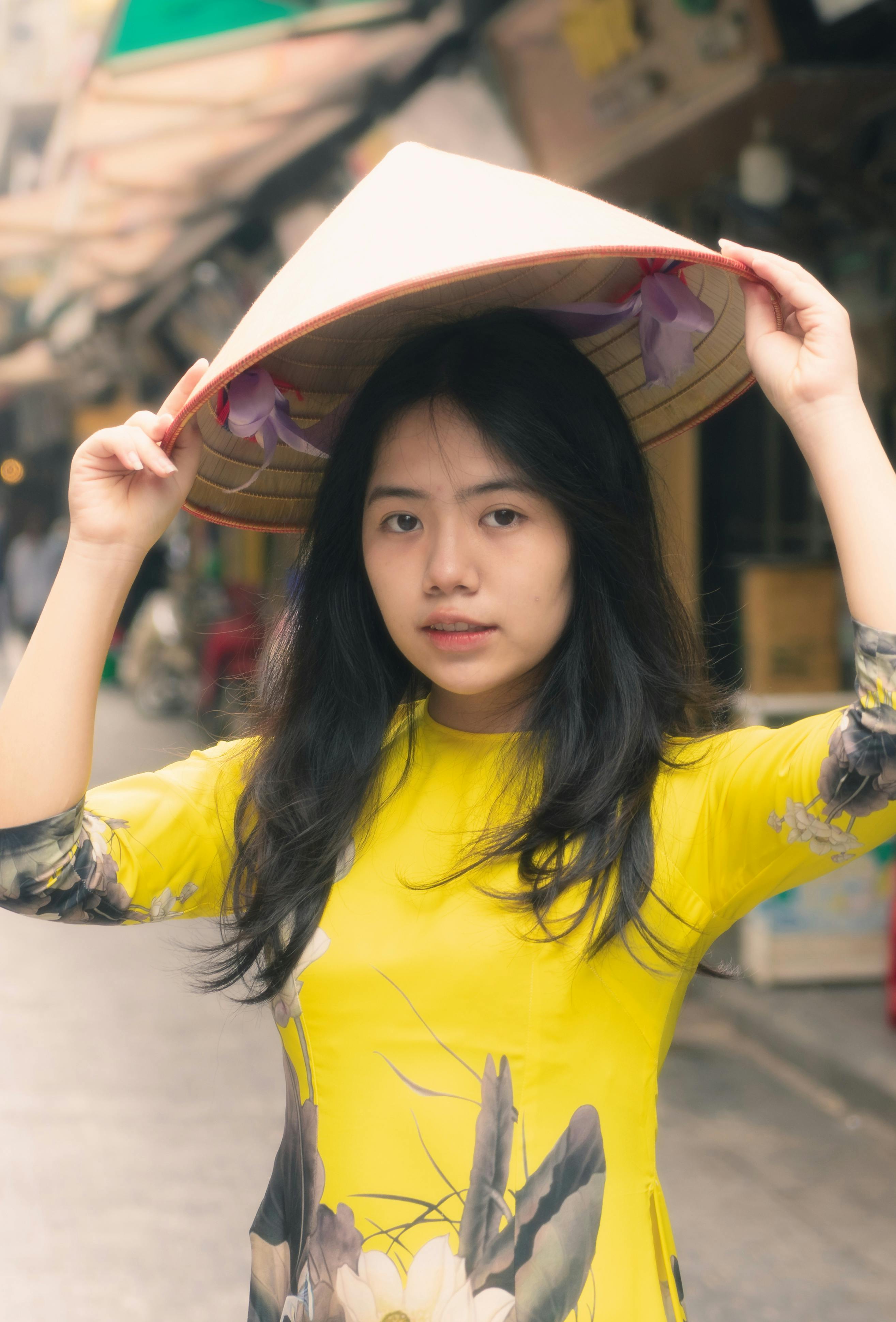 a pretty woman in yellow dress holding a hat