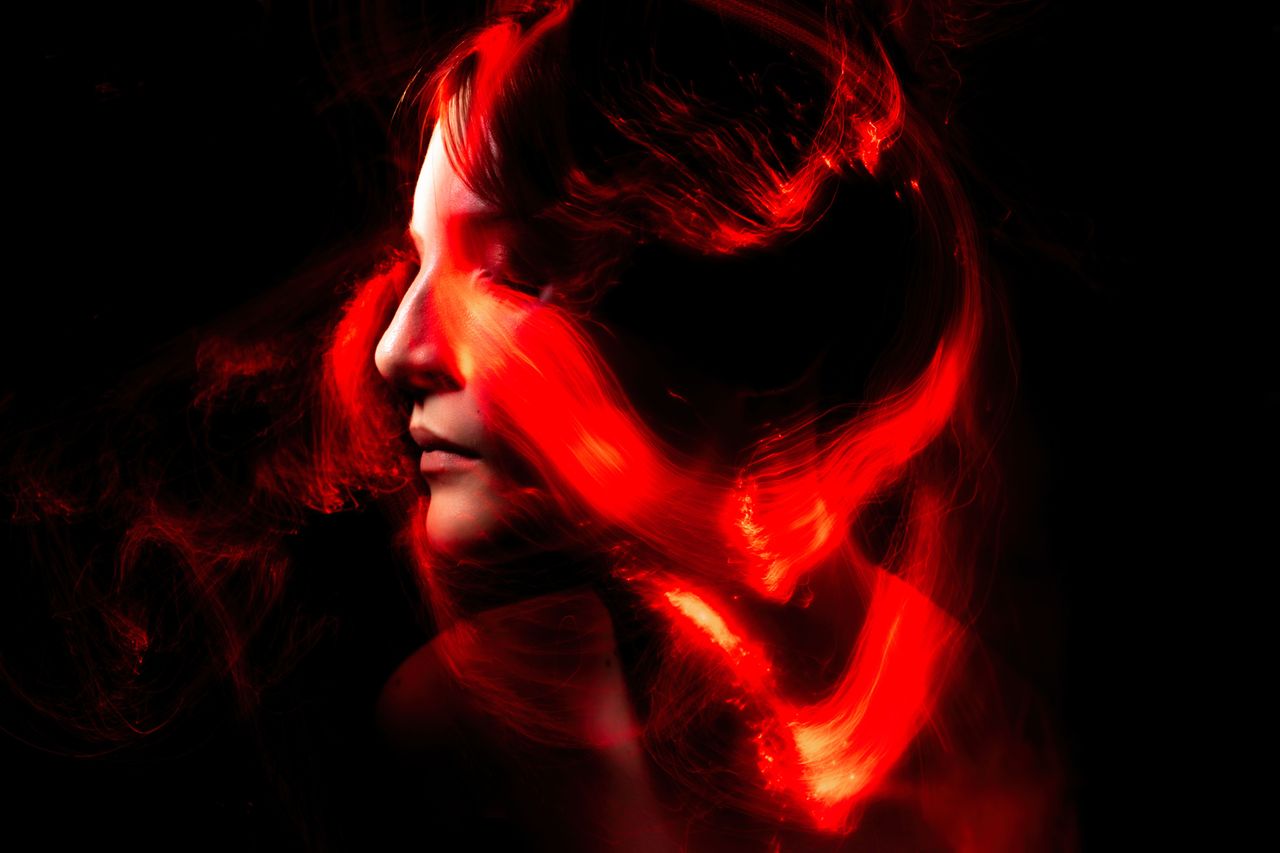 artistic portrait featuring red light trails swirling around a woman s
