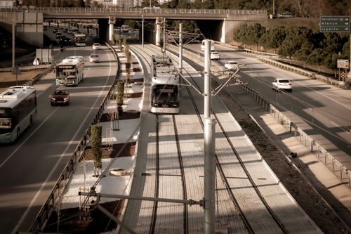 Free Captivating aerial view of a train alongside a busy highway with moving cars and buses. Stock Photo