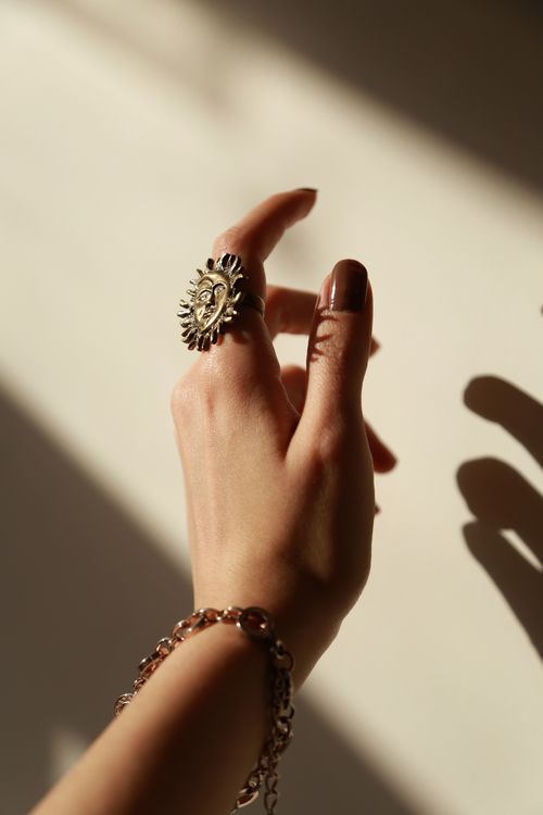 Free Close-up of a hand with a sunburst ring and bracelet in warm lighting. Stock Photo