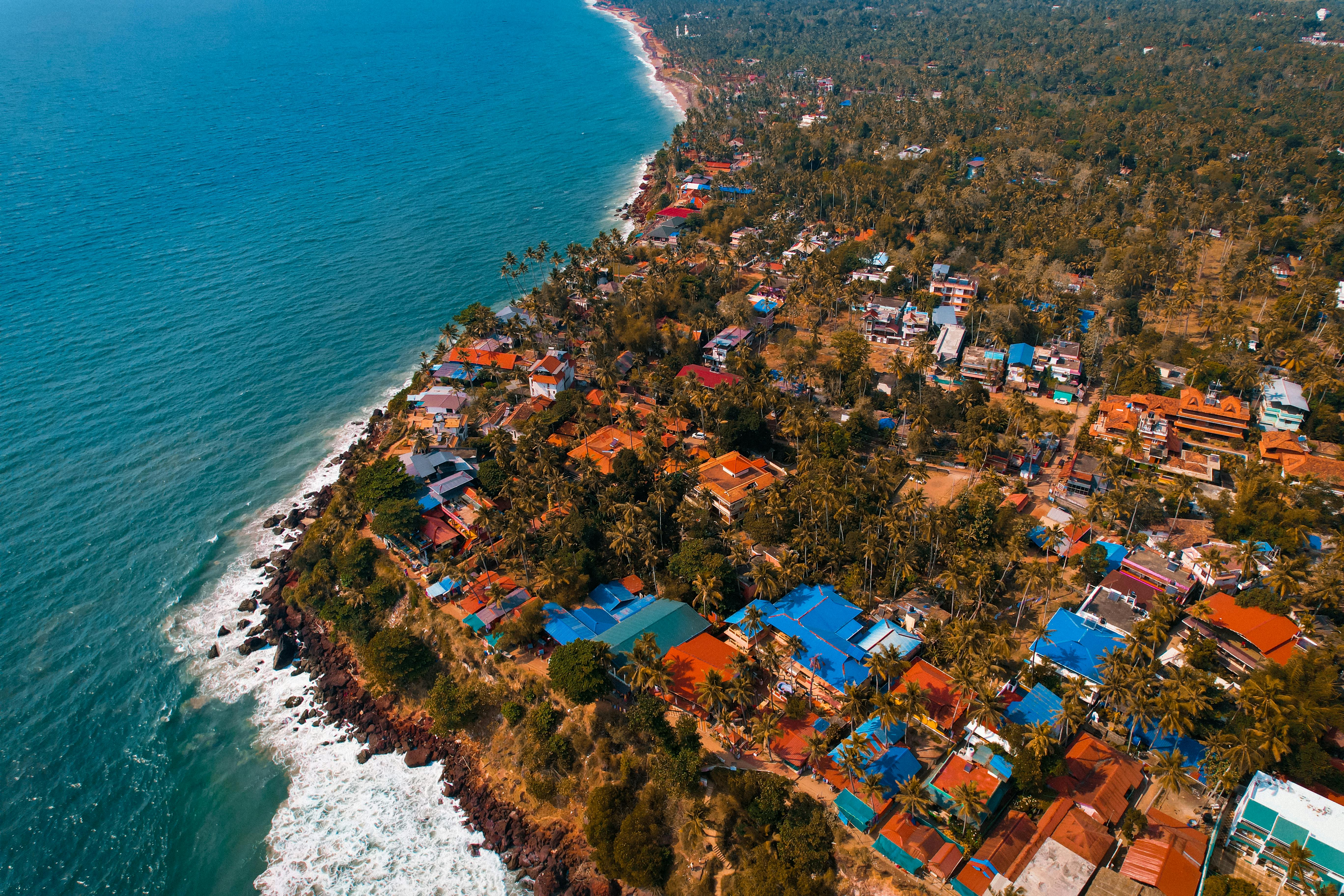 Scenic aerial shot of Varkala, a vibrant coastal village in Kerala, India, showing colorful houses and the Arabian Sea coastline.