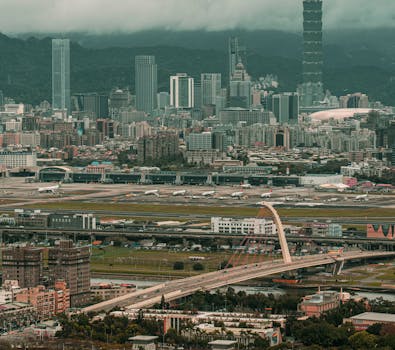 A stunning aerial capture of Taipei City showcasing its busy airport and iconic Taipei 101 skyscraper.