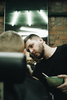Barber focuses on grooming a client's hair in a stylish urban salon with exposed brick and neon lighting.