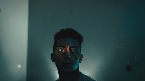 Free A moody portrait capturing a young man's thoughtful expression in low light. Stock Photo