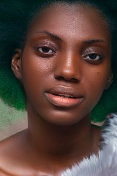 Close-up portrait of a woman with unique green hair and striking features, shot indoors.
