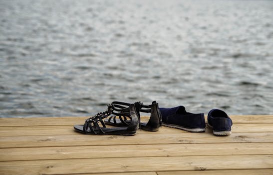 木制码头上放着一双凉鞋和鞋子，俯瞰着平静的湖泊