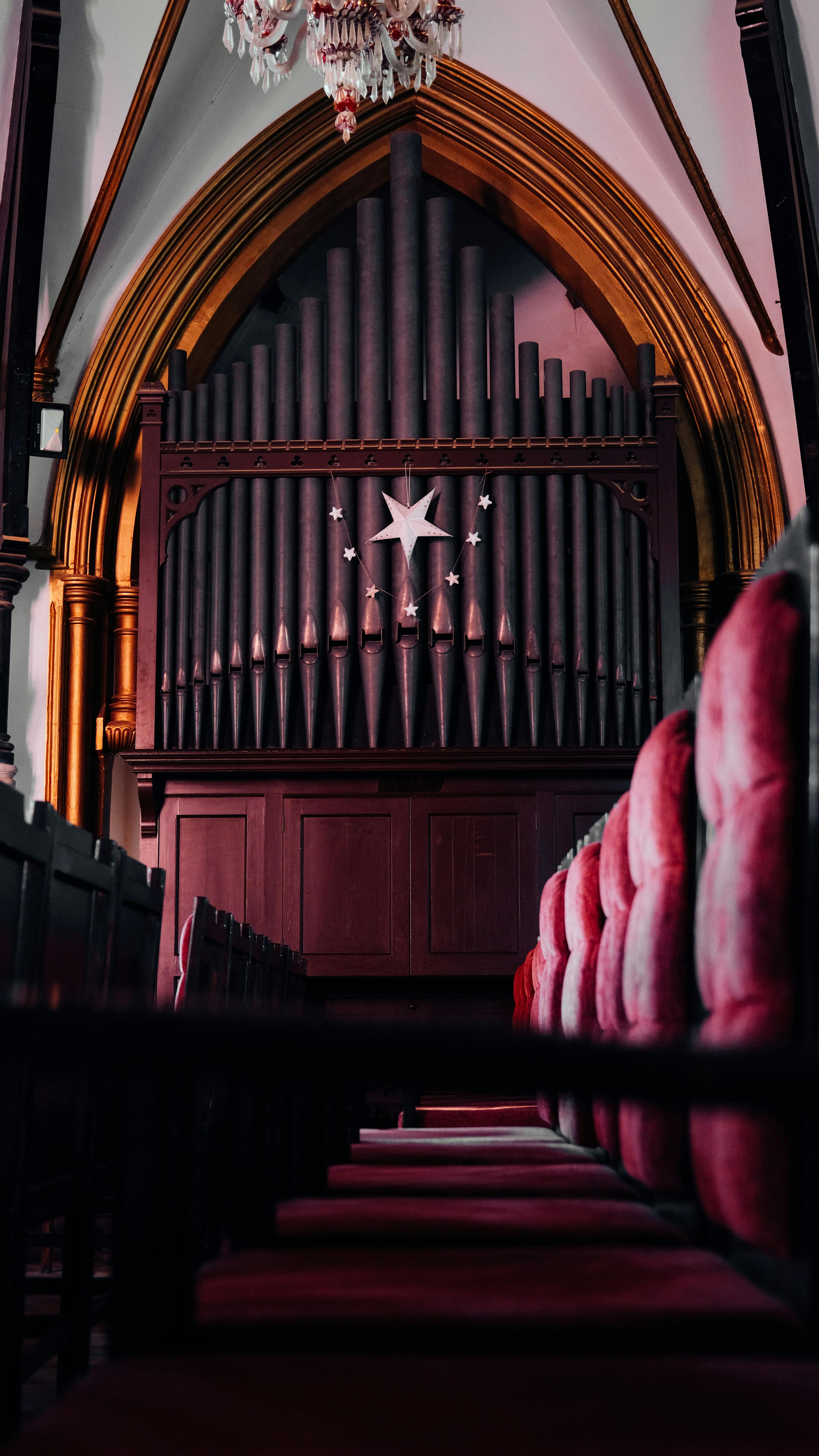 Majestic view of a church interior with ornate pipe organ architecture and red pews.