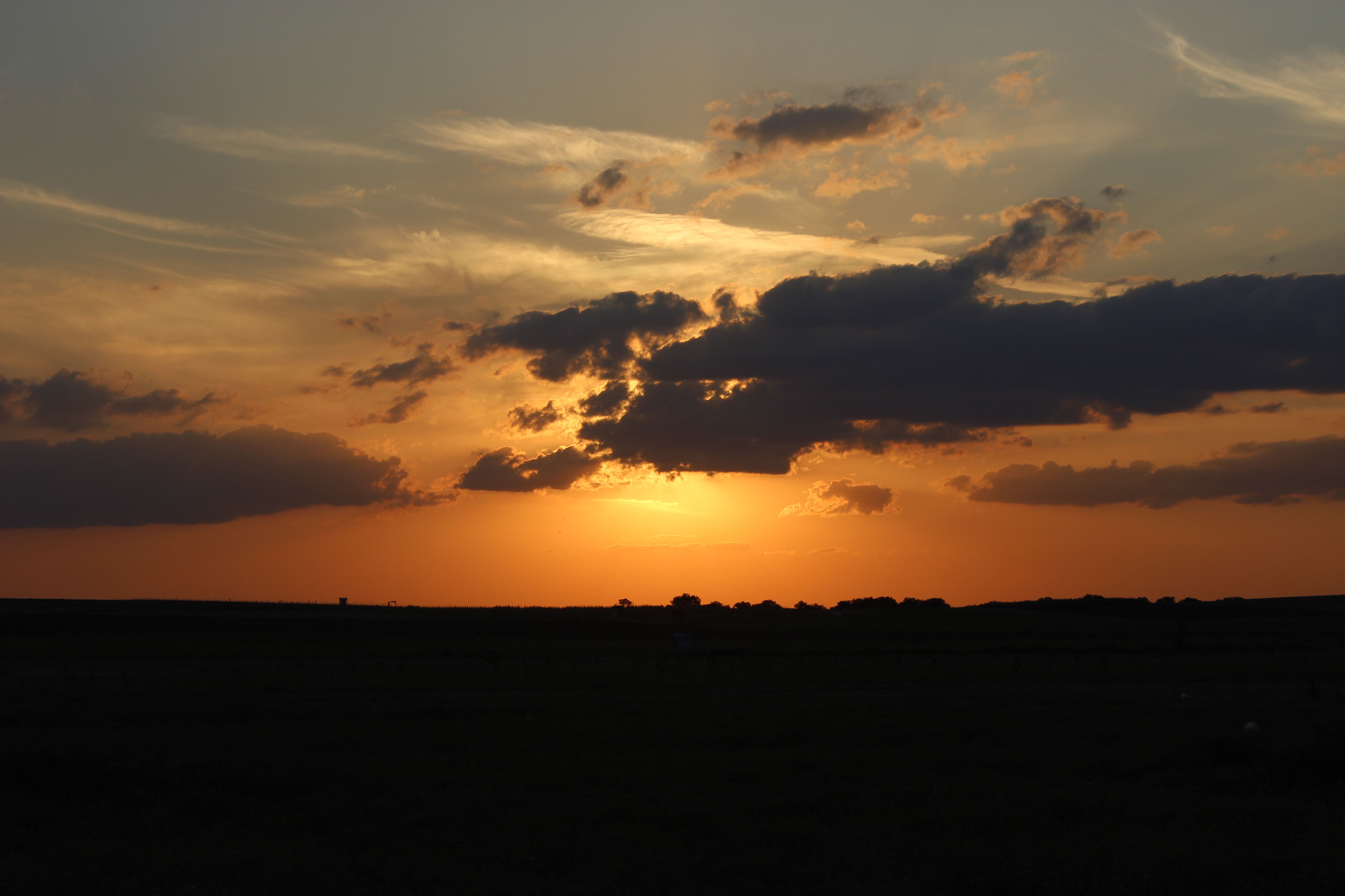 Captivating sunset with dramatic clouds and silhouettes in a serene natural setting.