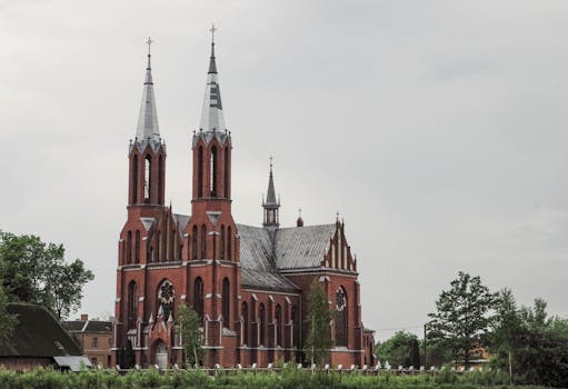A beautiful Gothic-style cathedral with tall spires, set against a cloudy sky in a quaint town.