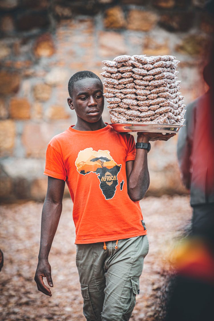 A Man Carrying Bags Of Peanuts On A Tray