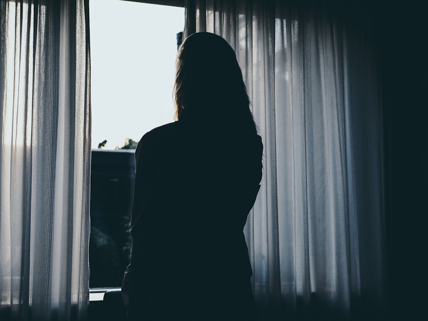 Silhouette Of Woman Standing Beside Window