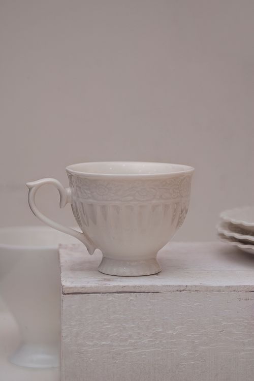 Free A close-up of a white ceramic teacup with intricate design, perfect for elegant serving. Stock Photo