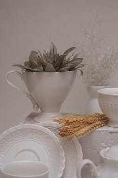 Aesthetic minimalism with ceramic dishes and dried flowers on a neutral backdrop, embodying elegance.