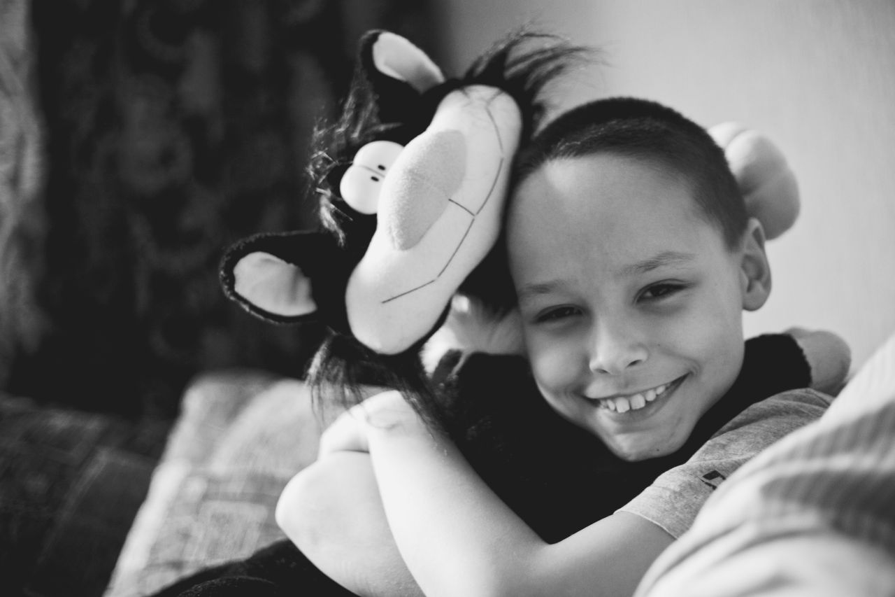 a smiling child warmly hugs a stuffed toy cat showcasing joy and innoc