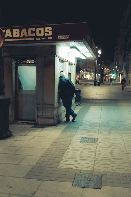 Free Man in black jacket at a kiosk captures the essence of urban nightlife. Stock Photo