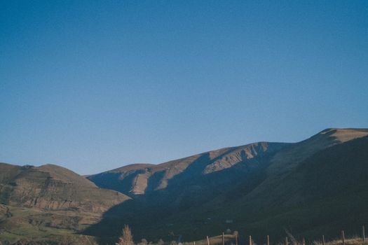 A serene mountain landscape with clear blue sky, showcasing natural beauty and tranquility.