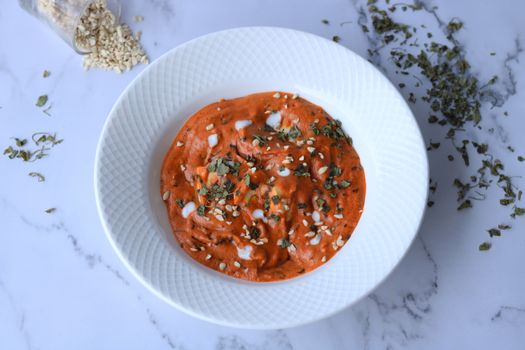 A vibrant muhammara dip garnished with herbs on a white plate, perfect for healthy snacks.